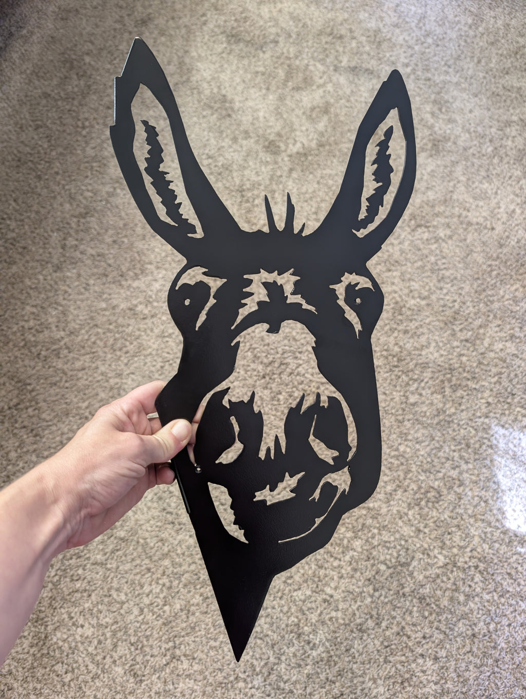 Hand holding the 17.5 inch black metal donkey head peeker to show its size