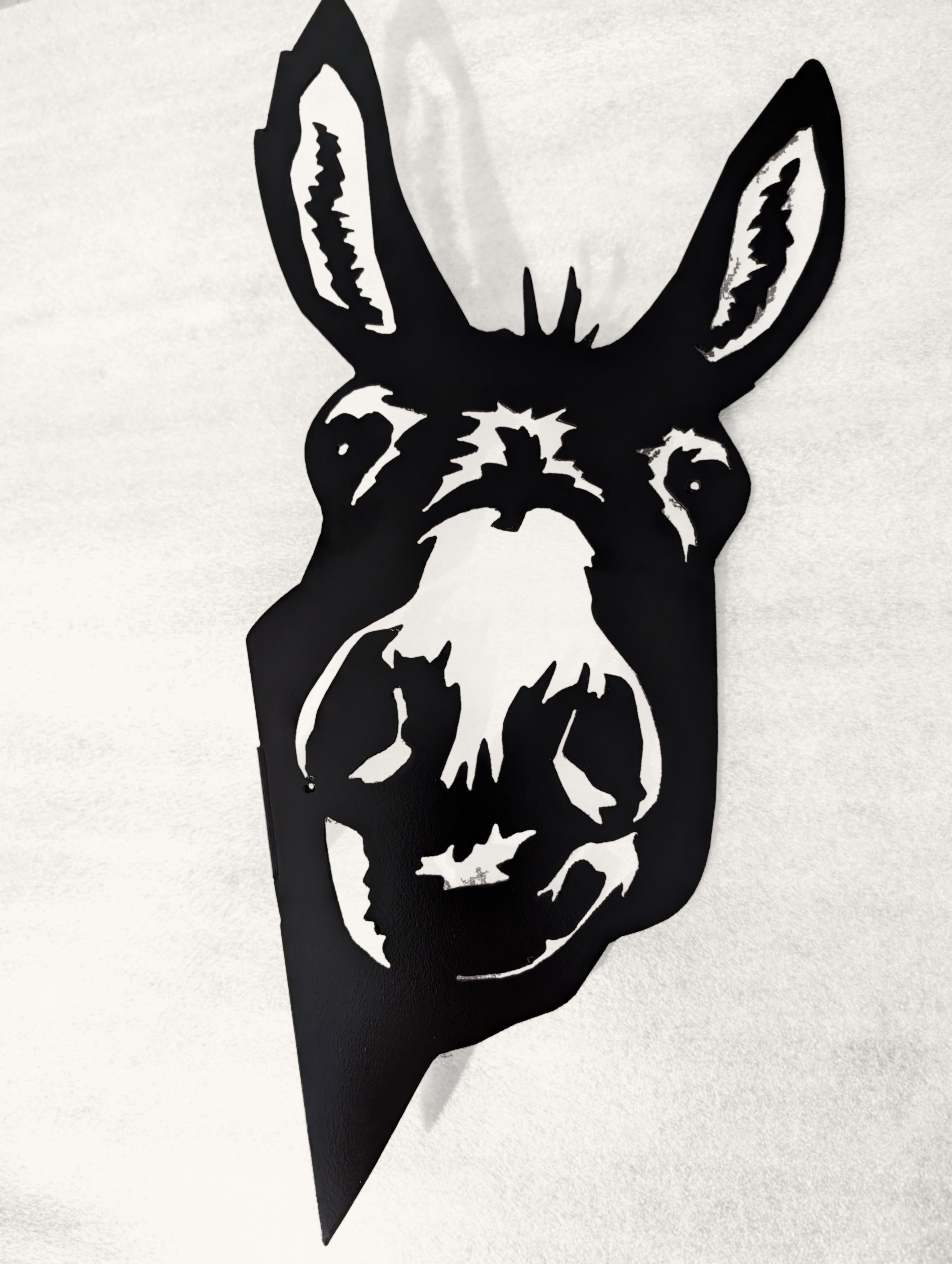 Black metal donkey head silhouette on a white background