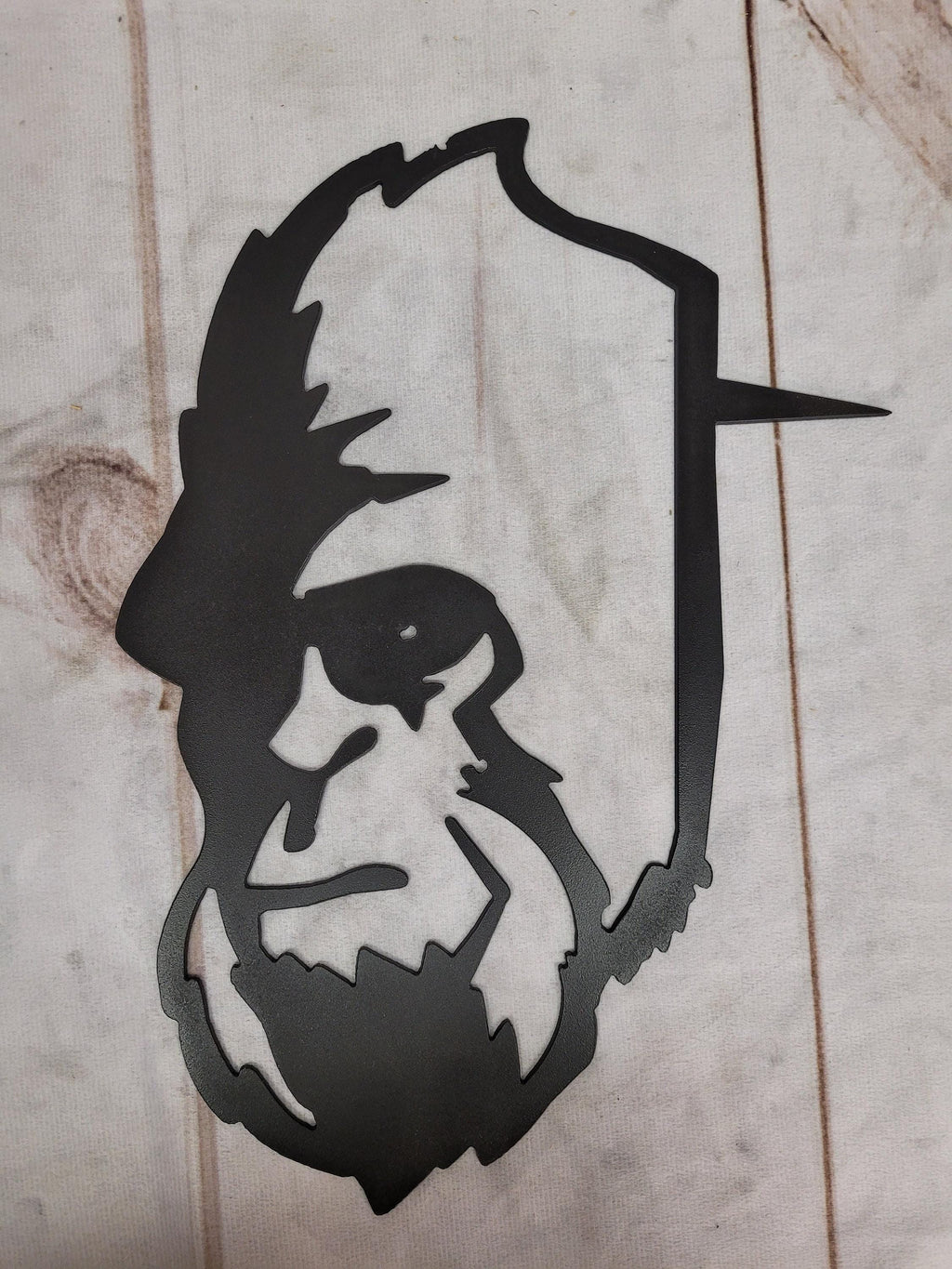 Bigfoot Dad Metal Stake Metal Garden Stake — shown on a rustic wall