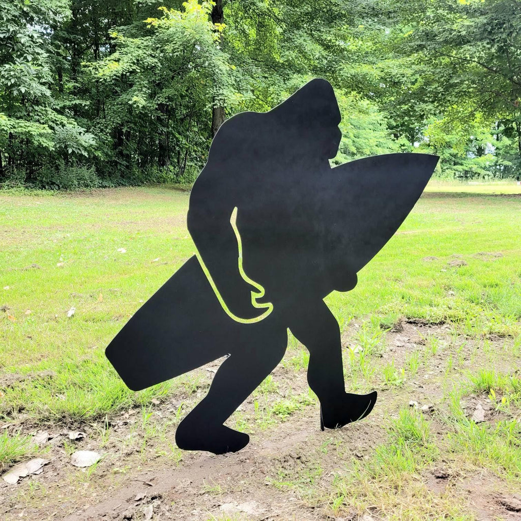 Surfing Bigfoot Metal Stake Metal Garden Stake — shown on a rustic wall