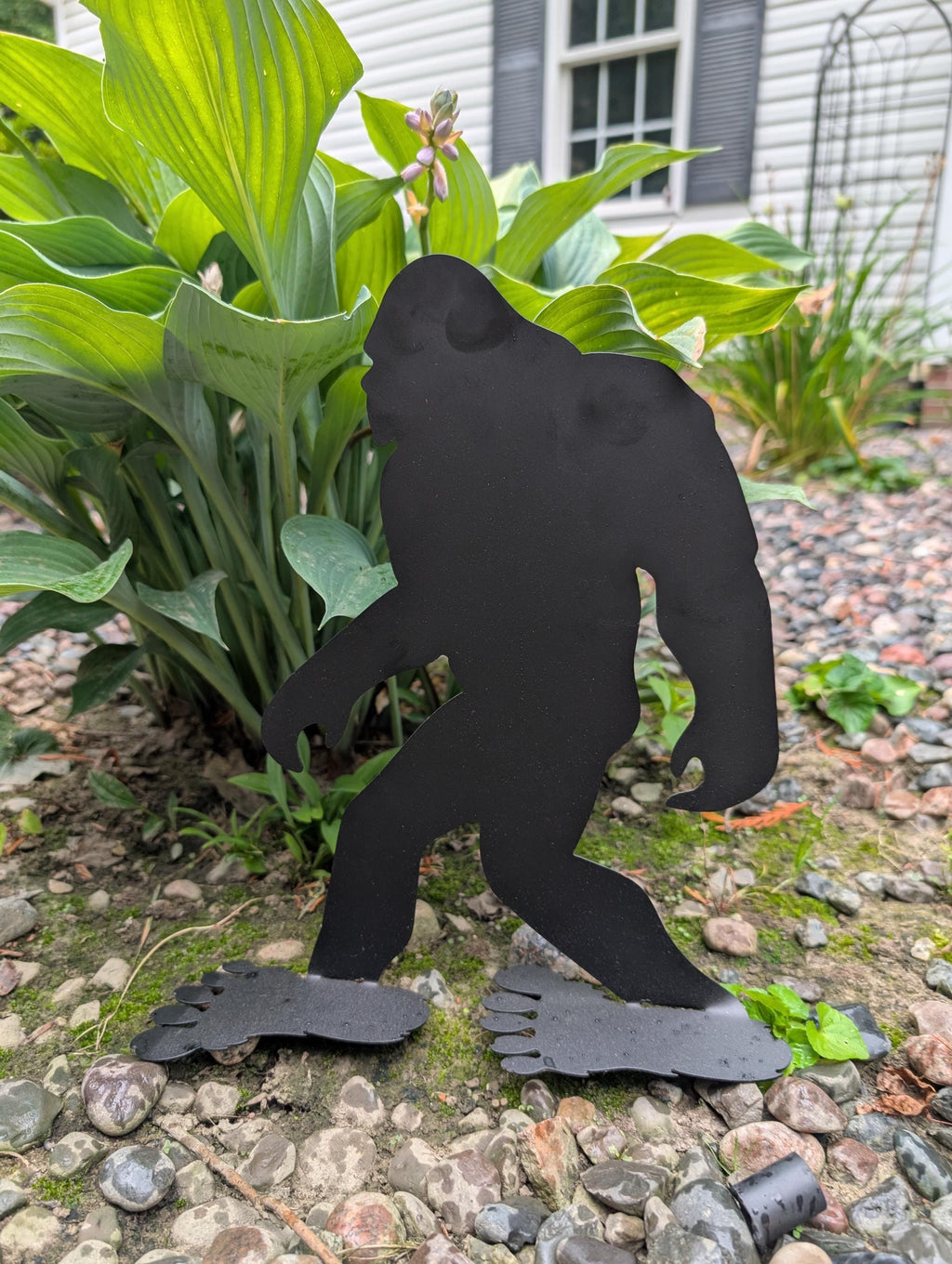 Bigfoot Desk Buddy Metal Yard Art Metal Garden Stake — shown on a rustic wall