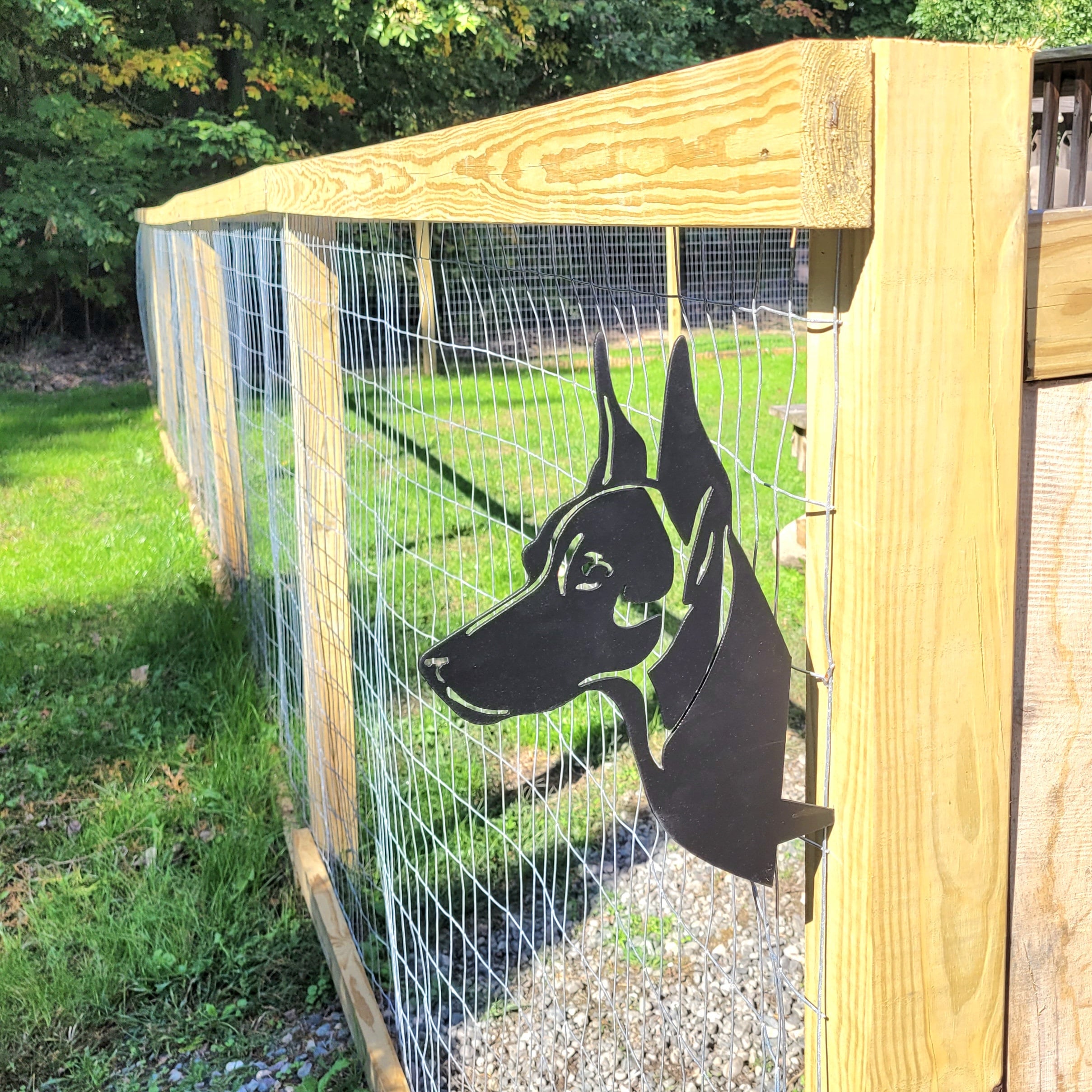 Doberman Peeking Pup Tree Stake Metal Garden Stake — shown on a rustic wall