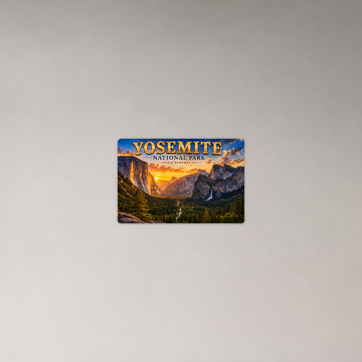 Sign showing Yosemite Tunnel View lettering with a granite valley and waterfall, displayed on a plain pale gray wall.