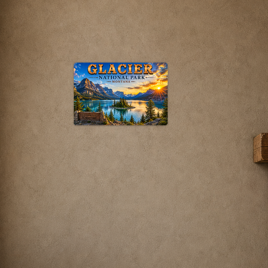 Sign showing Glacier Wild Goose Island St Mary Lake lettering and a pine-covered island in a mountain lake, displayed on a warm tan textured wall above a wooden ledge.