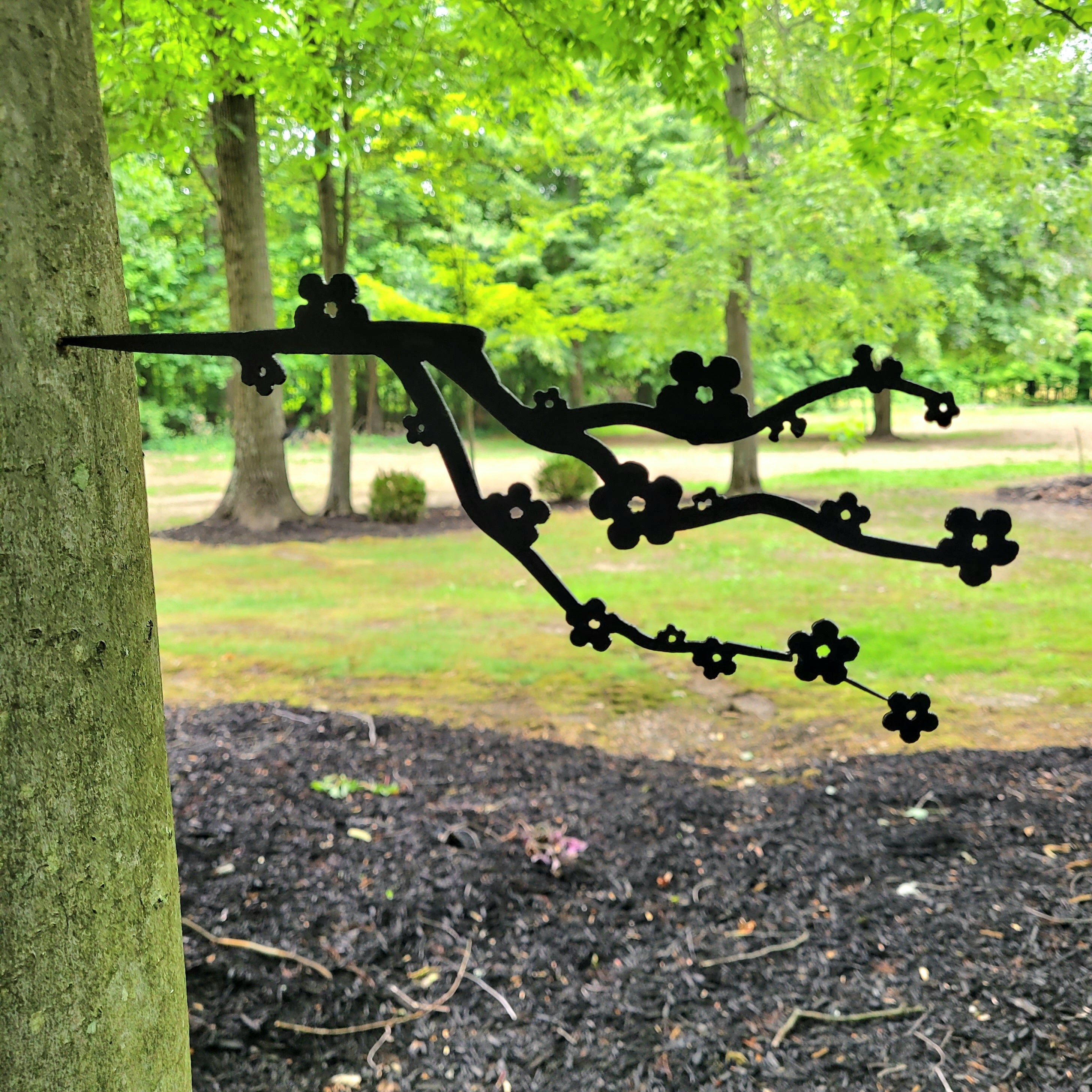 Flowering Branch Metal Garden Stake Metal Garden Stake — shown on a rustic wall