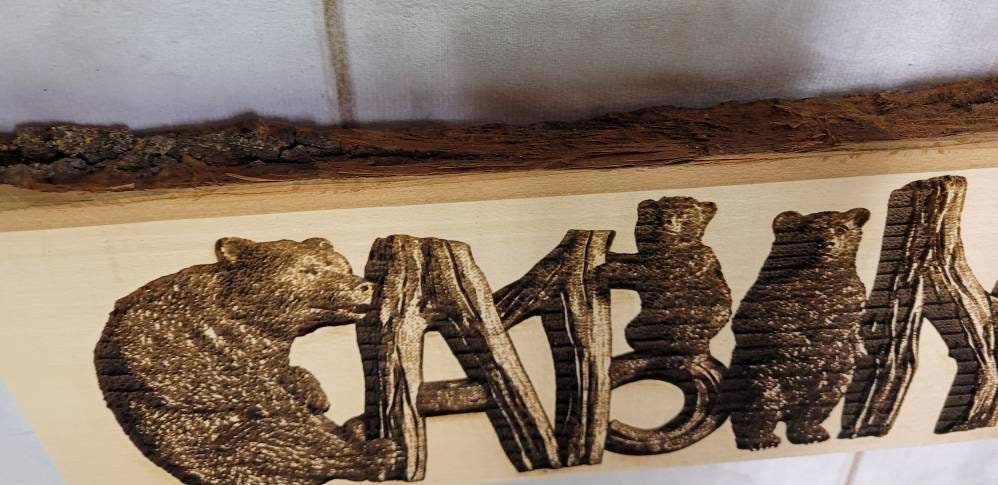 Laser Engraved Cabin with Bears Basswood Wall Wood Sign — shown on a rustic wall