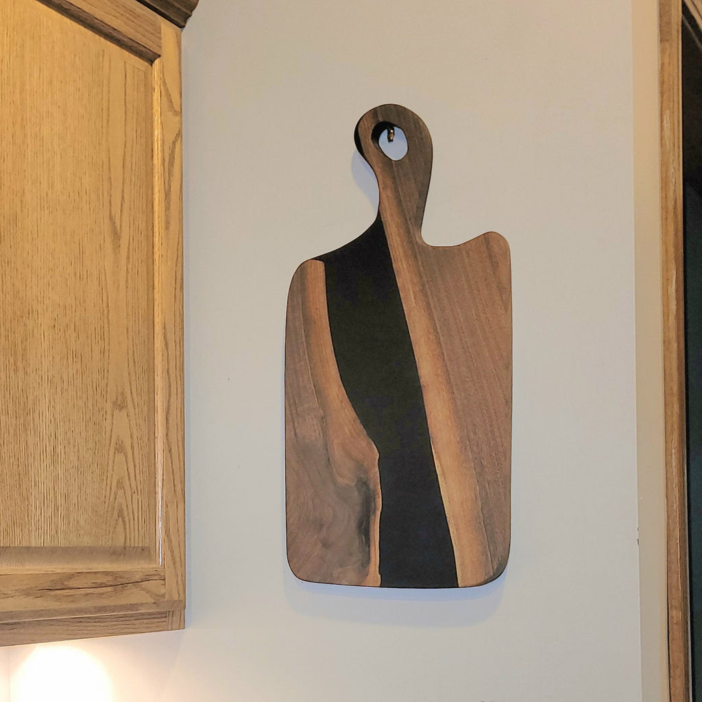 Live Edge Walnut Charcuterie Board: Black Epo Wood Sign — shown on a rustic wall