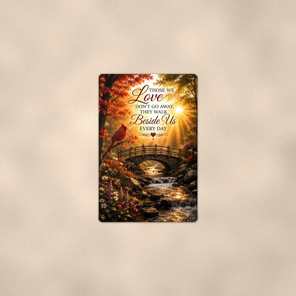 Cardinal over an autumn stream bridge memorial art titled "Those we Love don't go away, they walk Beside Us every day" on a 8x12 inch sublimated aluminum sign with rounded corners and mounting holes, shown at mid-distance centered on a warm wall