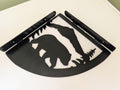 Pair of black metal bear shelf brackets laid flat, mirrored left and right, plasma cut bear, mountain and pine tree scene