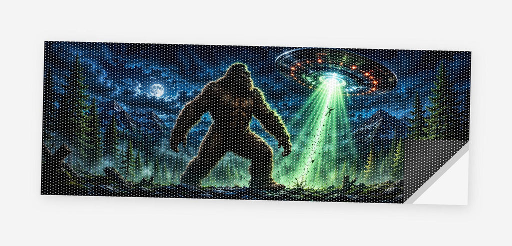 Full flat view of the Bigfoot UFO Abduction perforated truck window decal on a white background, one corner curled to show the black perf-vinyl backing and the micro-hole pattern