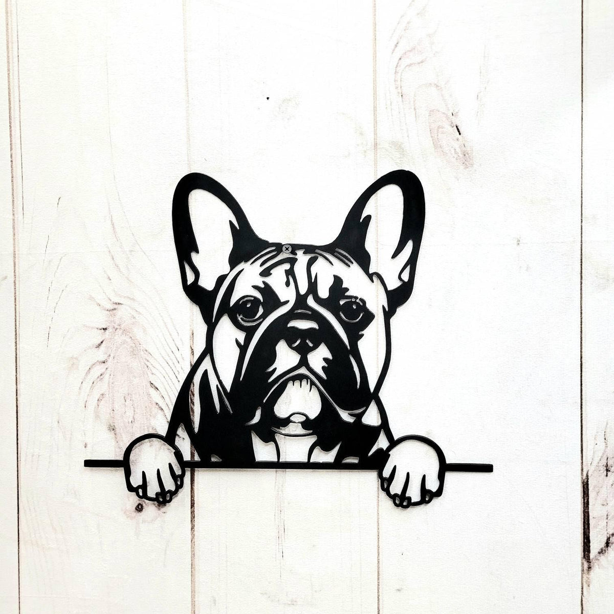 Black cutout of a dog with tall upright ears and two paws over a horizontal bar, mounted on white wooden boards.