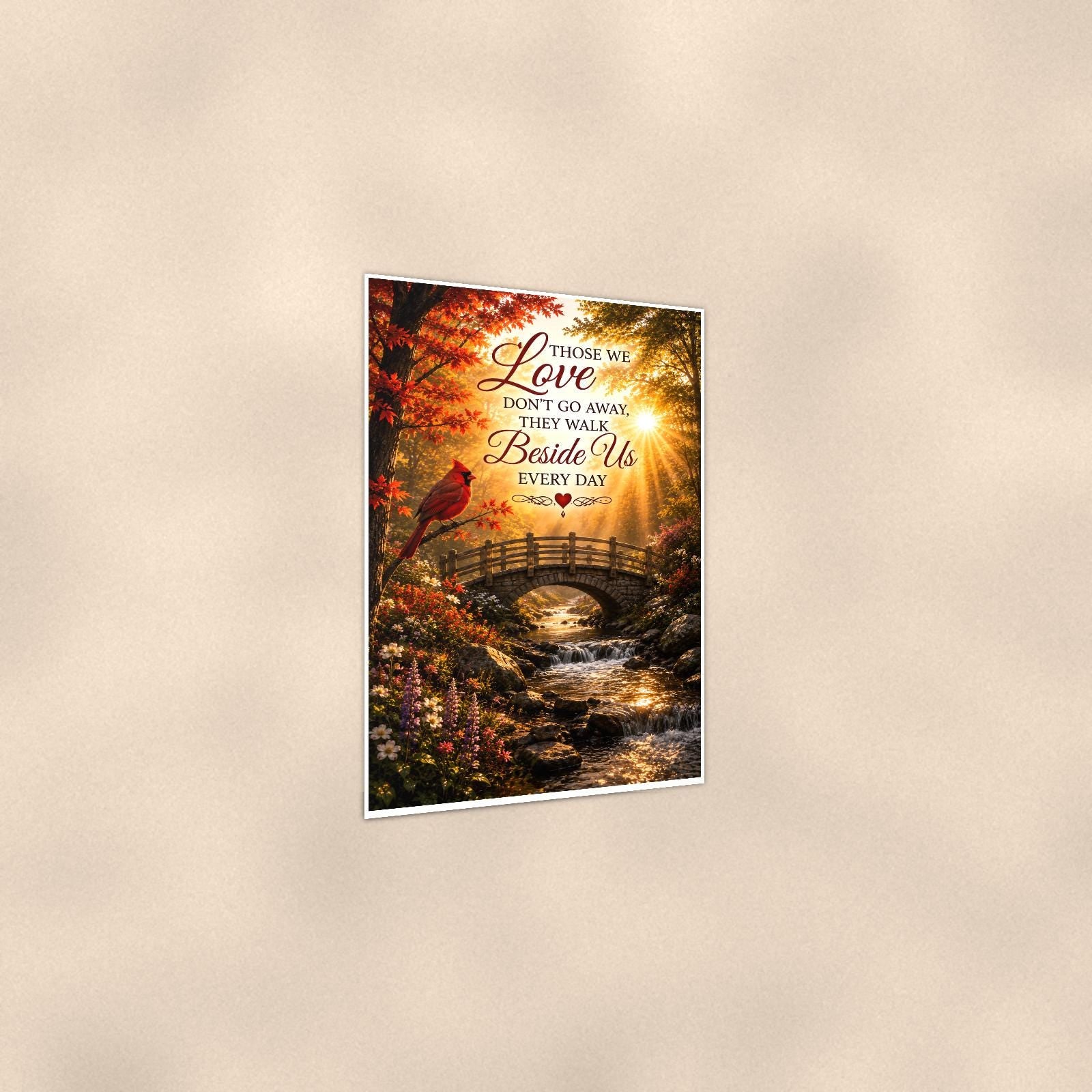 Cardinal over an autumn stream bridge memorial art titled "Those we Love don't go away, they walk Beside Us every day" on a 24x36 inch luster poster print with a clean white border, shown at a three-quarter angle on the wall