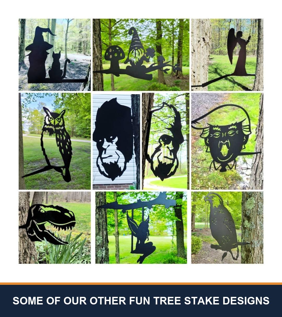 A sampler grid of other TKG metal tree and garden stake designs, shown staked in flower beds and mounted on trees, posts and mailboxes. Captioned “some of our other fun tree stake designs” — these are other designs we make, not what is included with this listing.