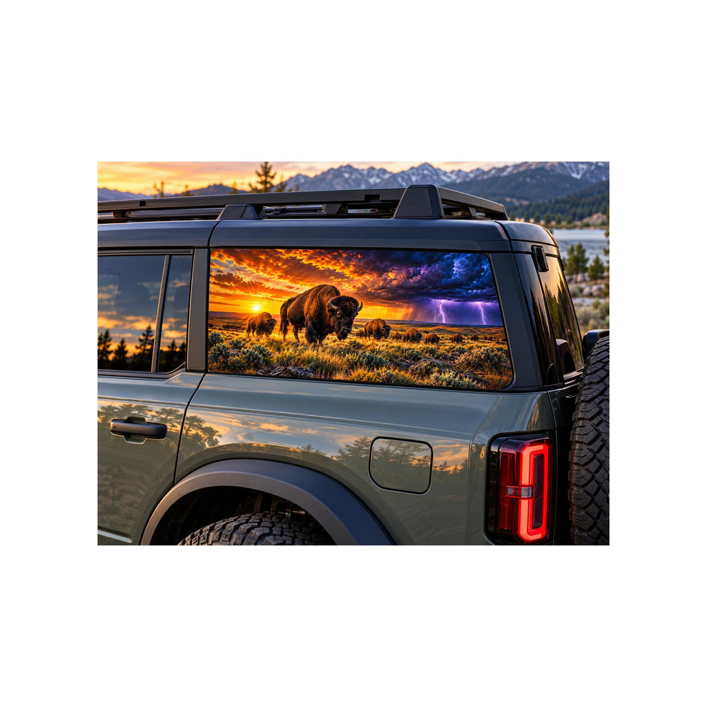 Ford Bronco rear side window with a perforated decal of a bison herd grazing on the prairie at sunset, a lightning storm with purple clouds rolling in on the right side of the scene, applied to the outside of the glass.