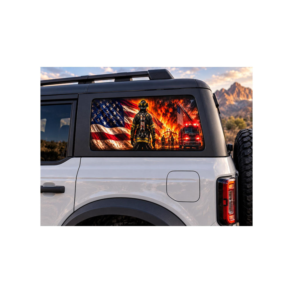 Ford Bronco rear side window with a perforated decal of a firefighter in full turnout gear standing before an American flag and a working structure fire, a fire truck and ladder in the background, applied to the outside of the glass.