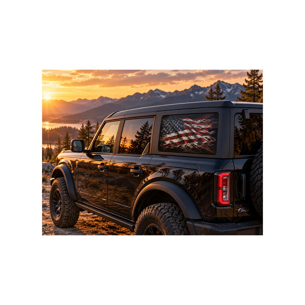 Ford Bronco rear side window with a perforated decal of a torn, grunge-style full-color American flag on a plain black background, applied to the outside of the glass.