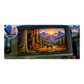 Jeep Wrangler 2-door rear side window with a perforated decal of Bigfoot peeking out from behind an autumn tree trunk, a whitetail deer standing in the meadow nearby, mountain sunset in the background, applied to the outside of the glass. An INCLUDED badge in the corner shows the felt squeegee and 2 American flag decals that come with every set.