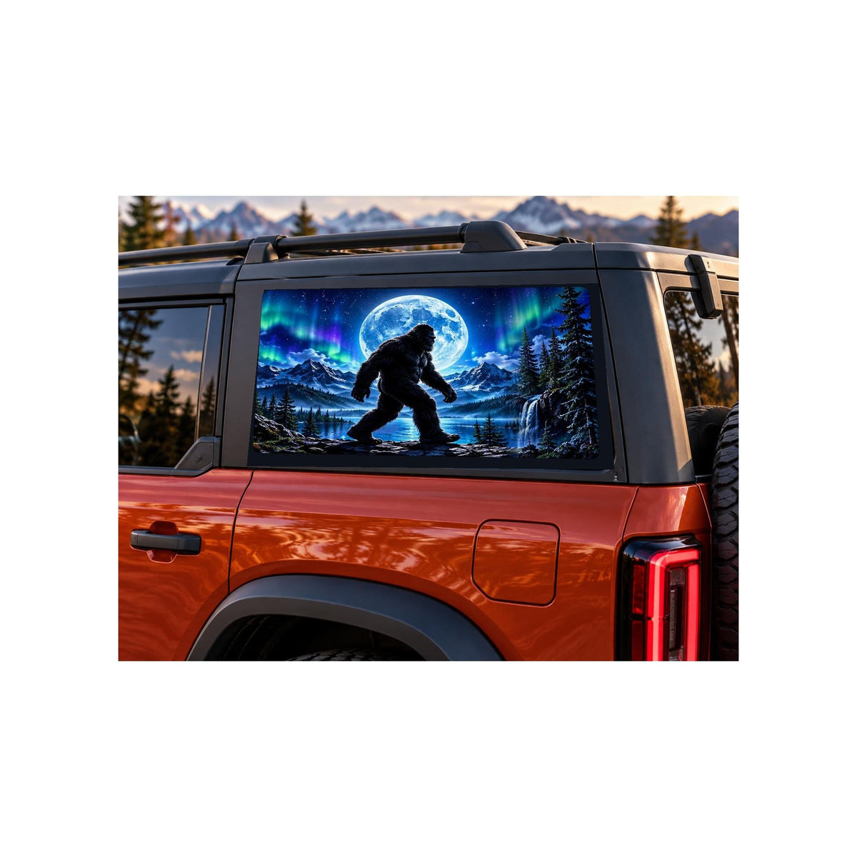 Ford Bronco rear side window with a perforated decal of Bigfoot walking beside a mountain lake under a full moon and green and purple northern lights, applied to the outside of the glass.