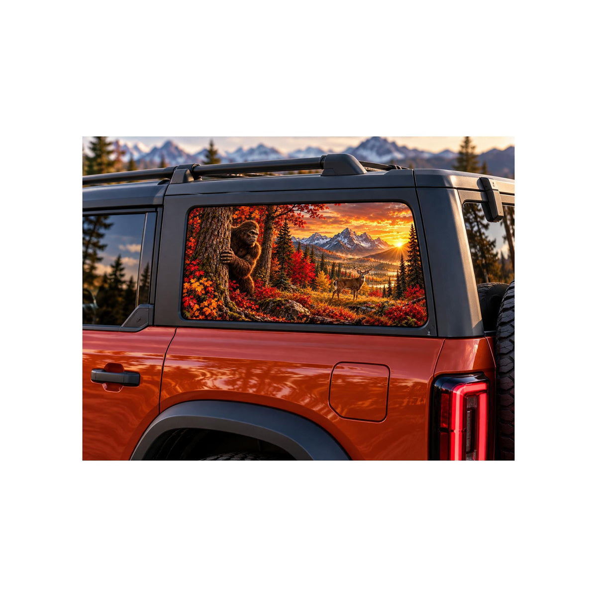 Ford Bronco rear side window with a perforated decal of Bigfoot peeking out from behind an autumn tree trunk, a whitetail deer standing in the meadow nearby, mountain sunset in the background, applied to the outside of the glass.